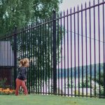 Girl look through fence on blue background, quarantine, suburb