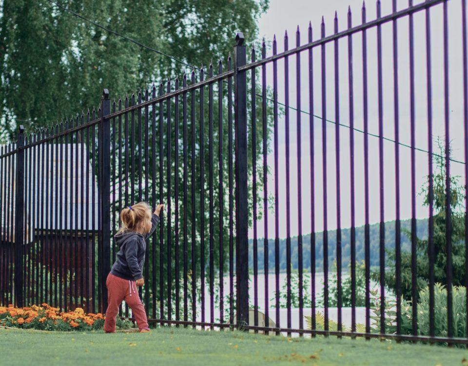 Girl look through fence on blue background, quarantine, suburb